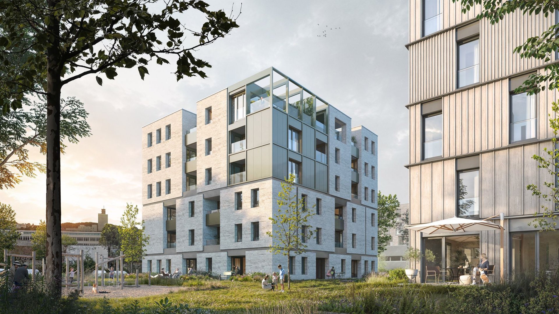 Innenhof mit Bäumen und Sitzplatz, im Hintergrund das Haus mit Loggien und Staffelgeschoss aus Metallpaneelen